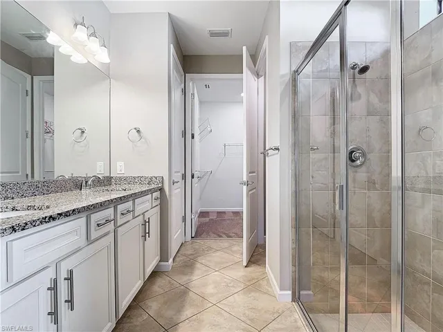 Bathroom with vanity, visible vents, a stall shower, a spacious closet, and tile patterned floors