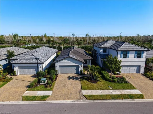 View of front of home featuring a front lawn, a tile roof, stucco siding, decorative driveway, and a garage
