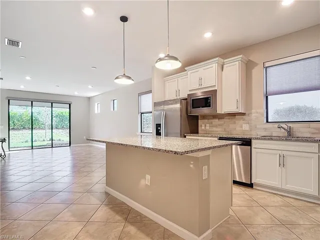 Kitchen featuring visible vents, a kitchen island, a sink, decorative backsplash, and stainless steel appliances
