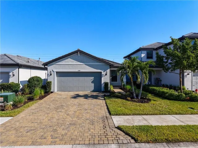 View of front of home featuring decorative driveway, a garage, a front lawn, and stucco siding