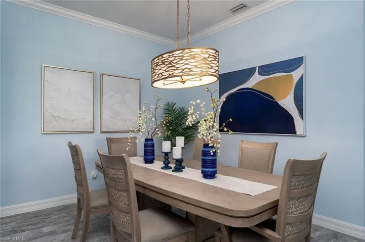 Dining area featuring light blue wall color, crown molding, and wood-finish flooring