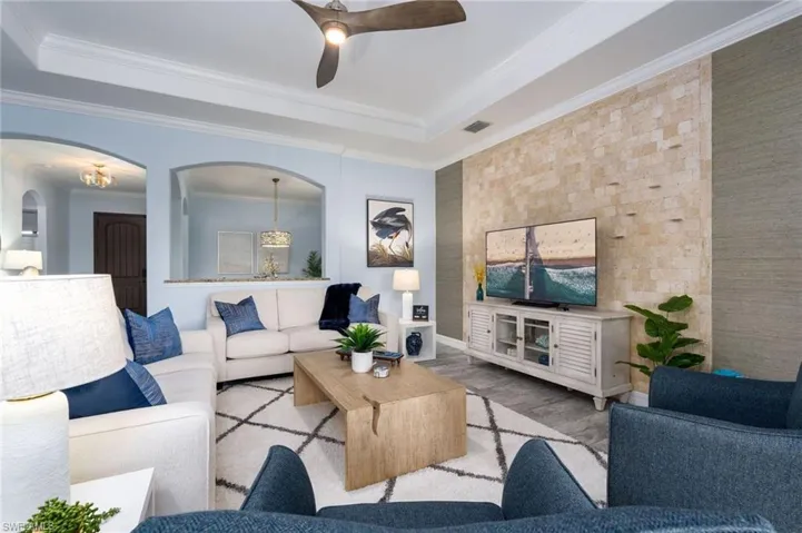 Living area featuring a tray ceiling with a ceiling fan, light blue wall paint, and wood-finish flooring