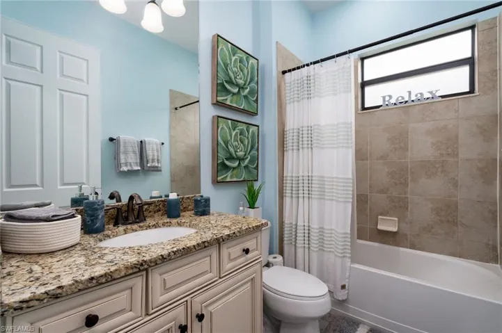Full bathroom featuring a single vanity with granite countertop, integrated sink, and white cabinetry