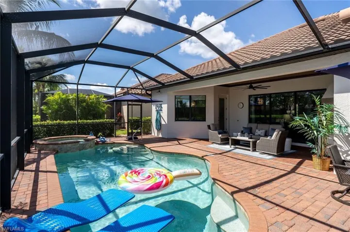 Screened pool and spa area featuring brick paver decking