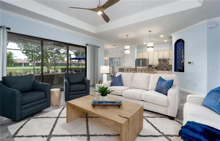 Open-concept living space featuring a tray ceiling with a ceiling fan, recessed lighting, and crown molding