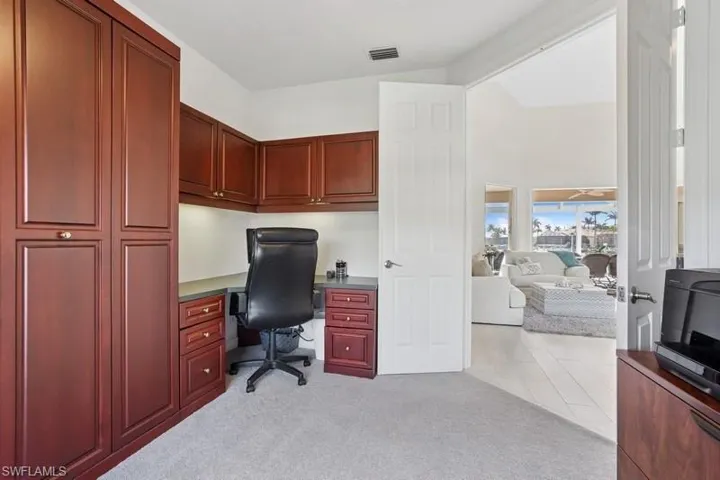 Office featuring built in desk, visible vents, and light carpet