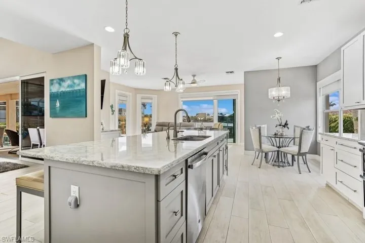 Kitchen featuring an inviting chandelier, dishwasher, a sink, and a center island with sink