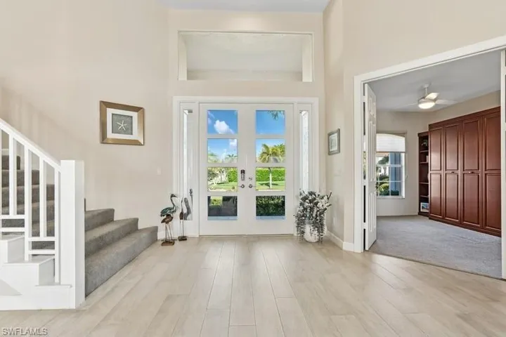 Foyer with baseboards, french doors, a ceiling fan, stairs, and light wood-style floors
