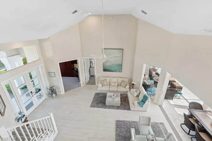 Living room featuring high vaulted ceiling, visible vents, french doors, and wood finished floors