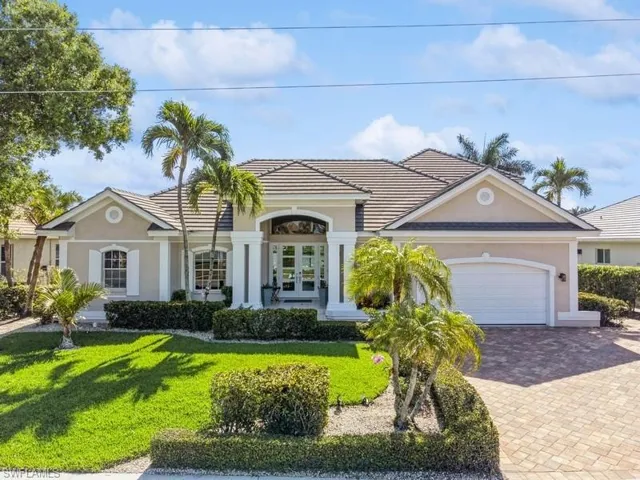 View of front of house with french doors, a front lawn, driveway, and stucco siding