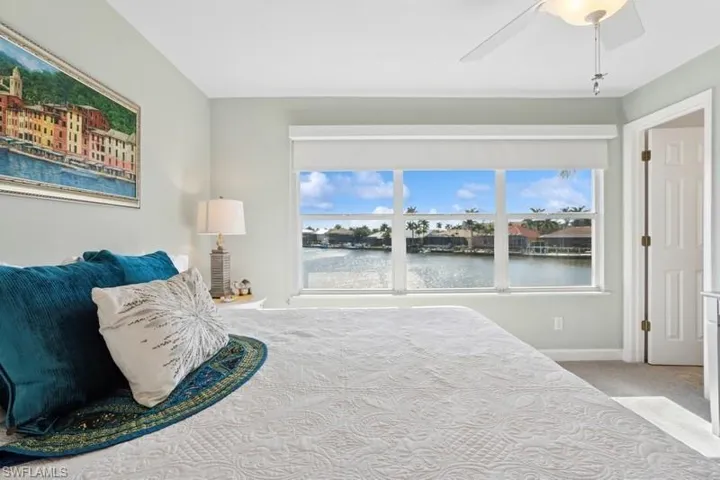 Carpeted bedroom with baseboards, a ceiling fan, and a water view