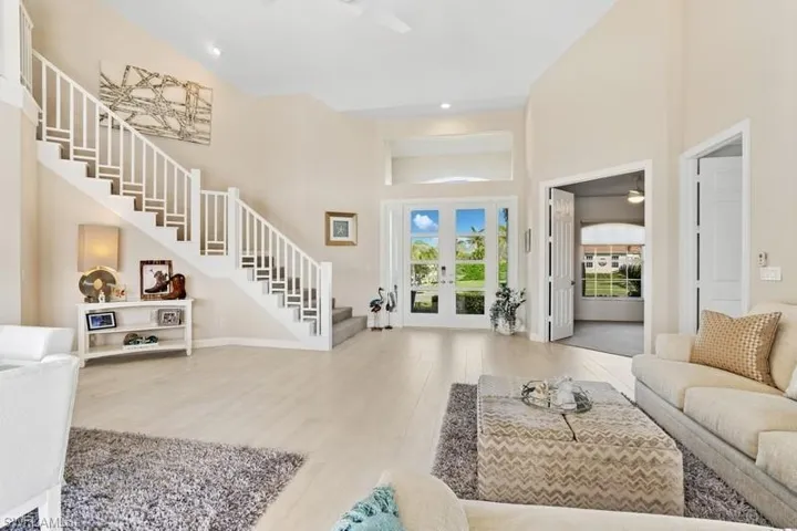 Foyer with high vaulted ceiling, a ceiling fan, stairway, wood finished floors, and french doors