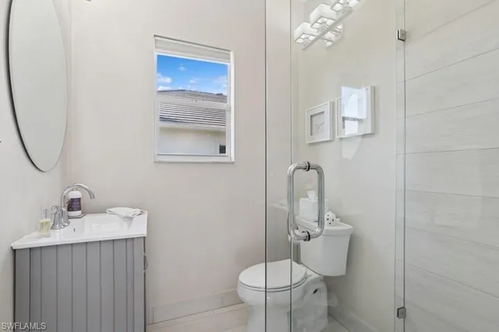 Bathroom featuring toilet, vanity, baseboards, and tile patterned flooring