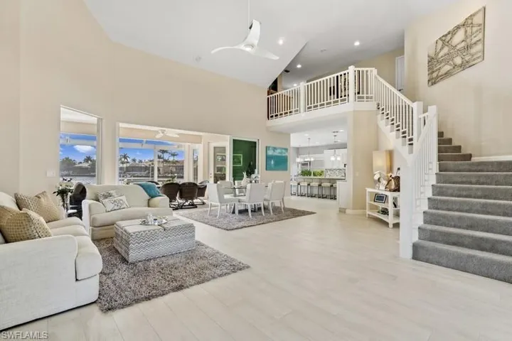 Living area with a ceiling fan, recessed lighting, a towering ceiling, wood finished floors, and stairs
