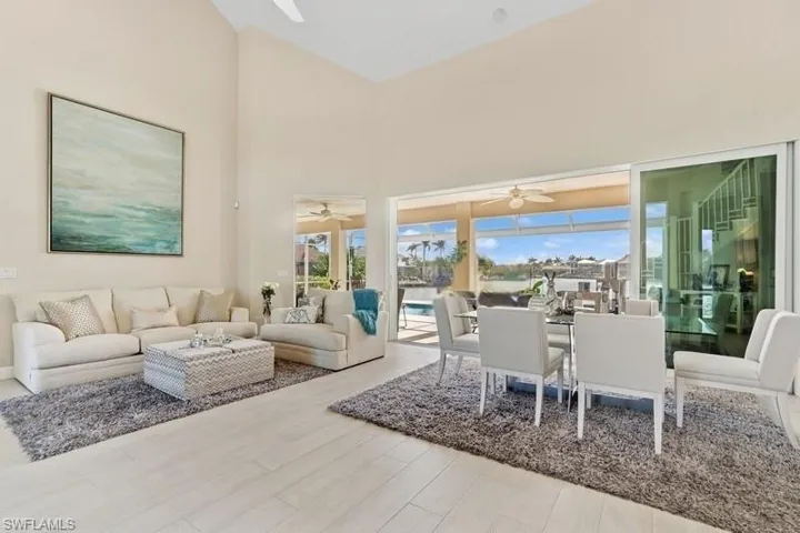 Living area featuring a ceiling fan, a high ceiling, and wood finished floors