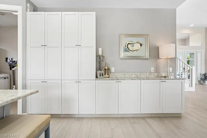 Kitchen featuring white cabinetry, french doors, light wood finished floors, and light stone counters