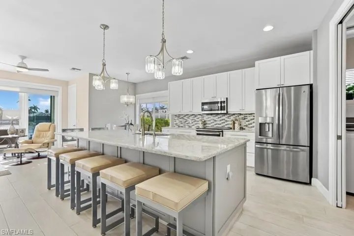 Kitchen with a sink, decorative backsplash, white cabinetry, and stainless steel appliances