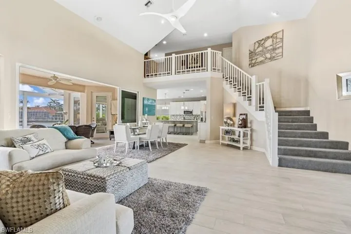 Living area featuring light wood-style flooring, visible vents, ceiling fan, and stairs