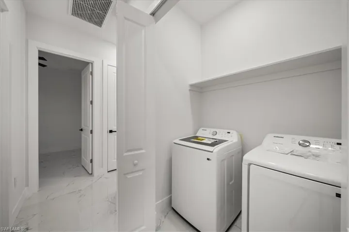 Laundry room featuring light marble finish floors and washing machine and clothes dryer