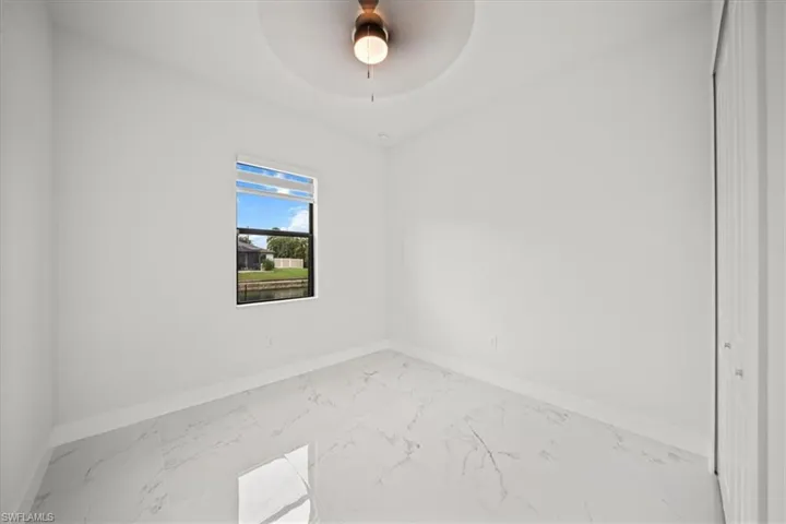 Unfurnished room with marble finish floors and a ceiling fan
