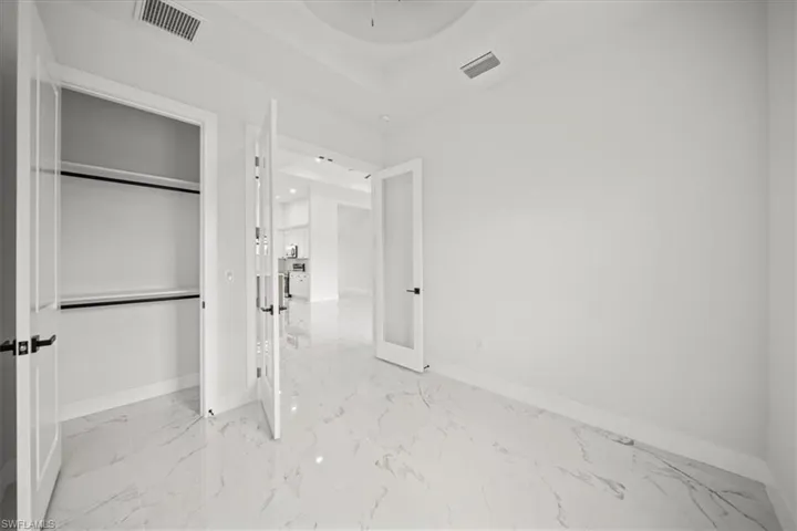 Unfurnished bedroom with light marble finish floors, a raised ceiling, and a closet