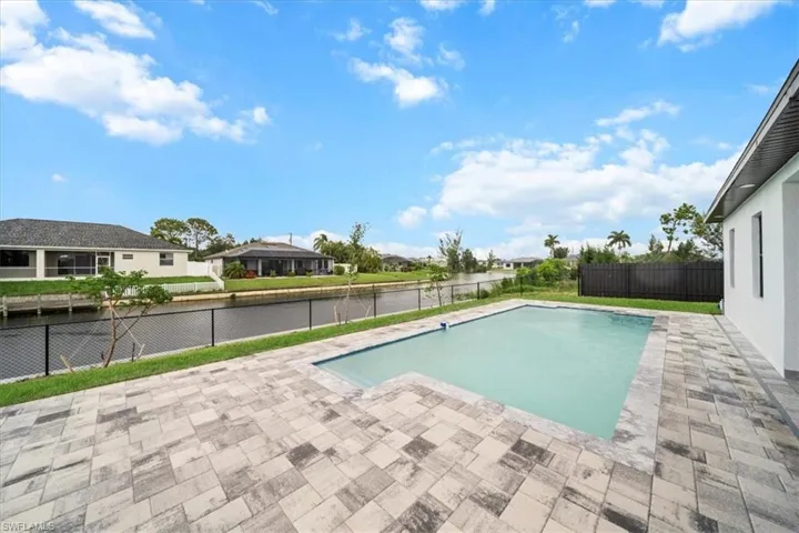 View of pool featuring a water view, a patio, a fenced backyard, and a residential view