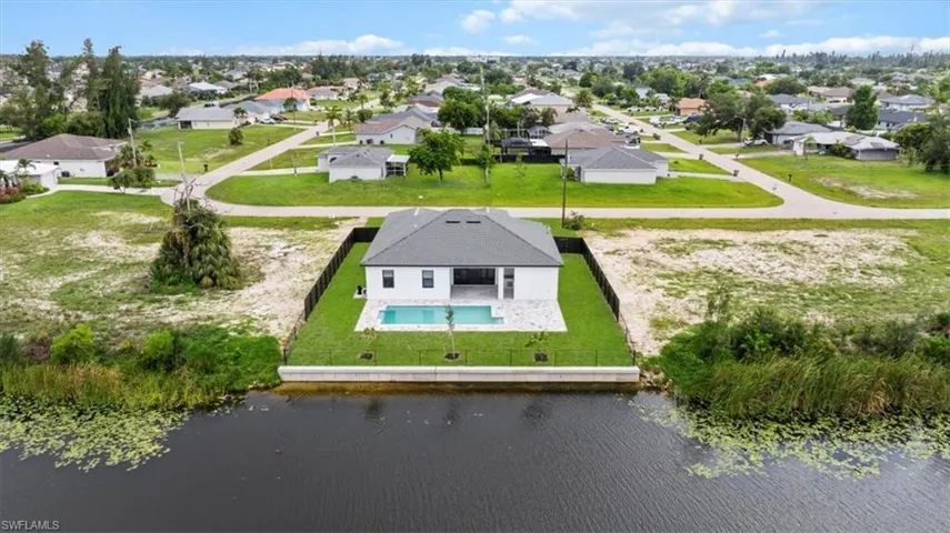 Aerial perspective of suburban area with a pool and a nearby body of water