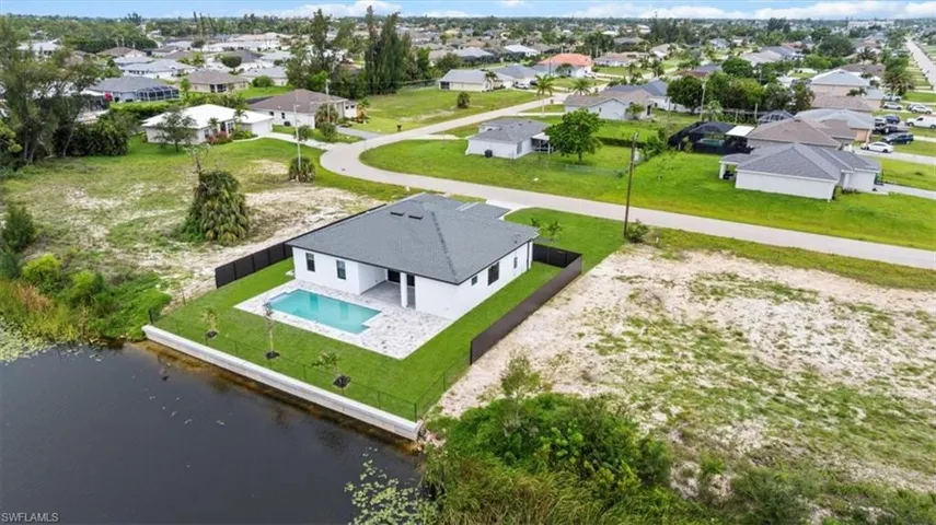 Aerial perspective of suburban area featuring a pool and a large body of water