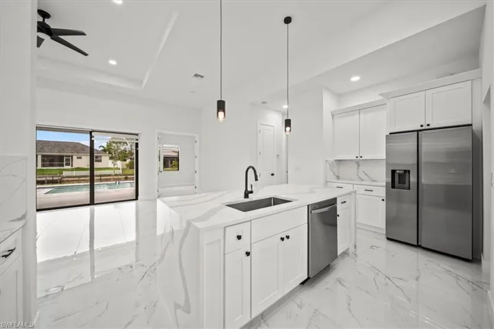 Kitchen with stainless steel appliances, white cabinetry, light marble finish flooring, light stone countertops, and recessed lighting