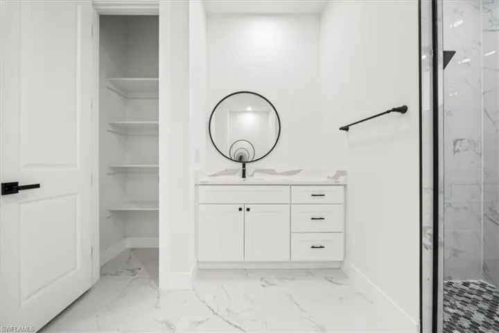 Bathroom with light marble finish flooring, vanity, and a marble finish shower