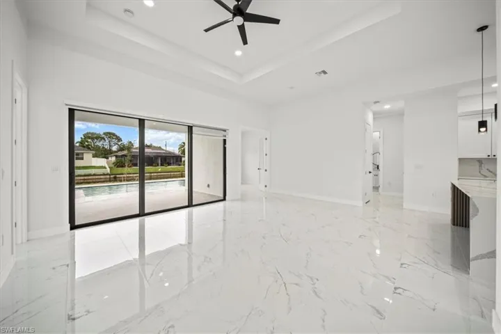 Spare room with a raised ceiling, recessed lighting, light marble finish floors, and a ceiling fan