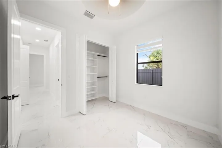 Unfurnished bedroom featuring light marble finish flooring and a closet