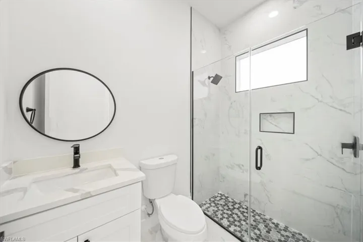 Outdoor pool bathroom with marble-finished vanity and shower