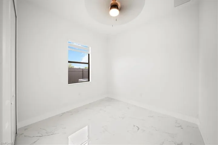 Unfurnished room with marble look tiles and a ceiling fan