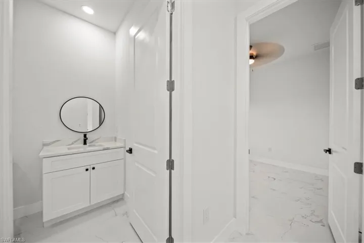 Half bath with light marble finish flooring, vanity, and recessed lighting