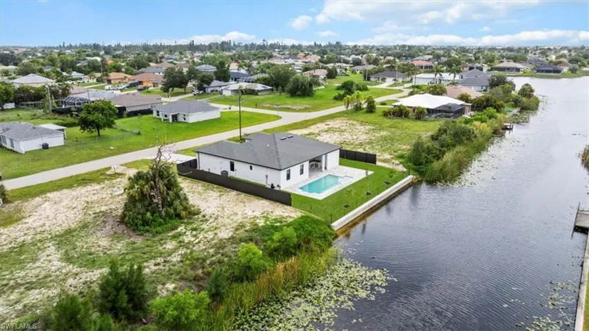 Aerial view of residential area with a pool and a large body of water