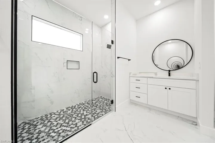 Full bathroom featuring a marble finish shower, vanity, light marble finish floors, and recessed lighting