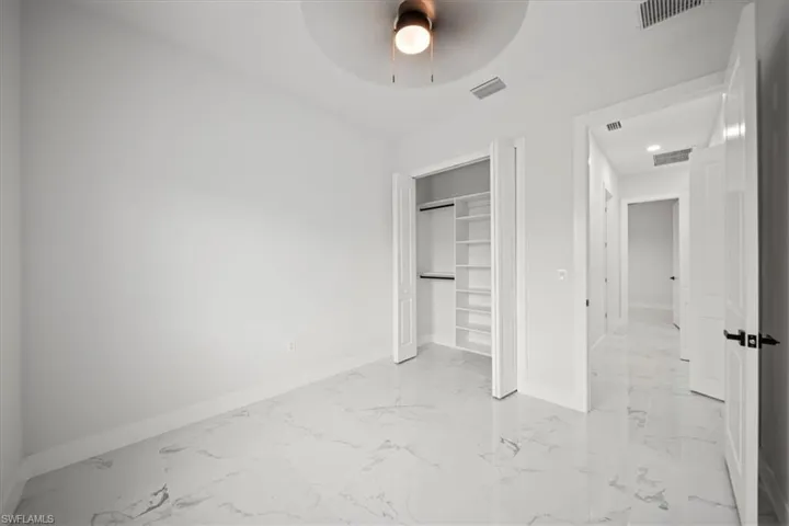 Unfurnished bedroom with light marble finish flooring, a closet, and ceiling fan