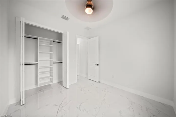 Unfurnished bedroom with a closet, light marble finish flooring, and a ceiling fan