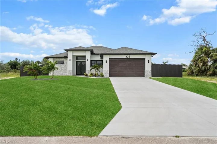 Prairie-style house with stone siding, stucco siding, concrete driveway, and a garage