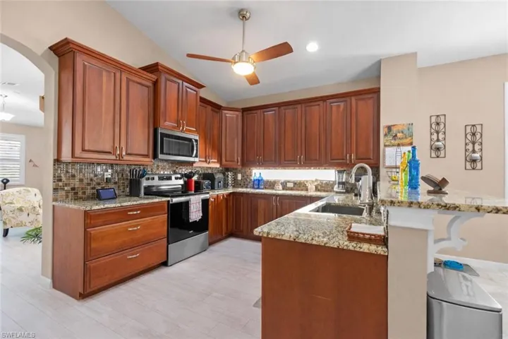 Kitchen featuring a breakfast bar, granite counters, stainless steel appliances, and wood finish cabinets