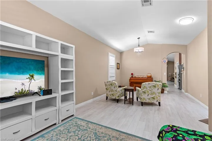 Living area featuring arched walkways, vaulted ceiling, and laminate wood-type flooring