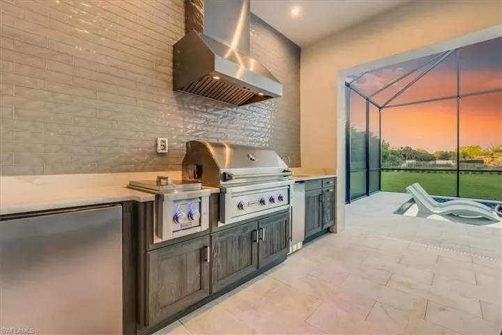 Outdoor kitchen with a gas grill, gas burners, ice maker, sink, and refrigerator.