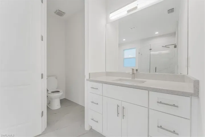 Bathroom with a marble finish shower, marble finish flooring, vanity, and recessed lighting