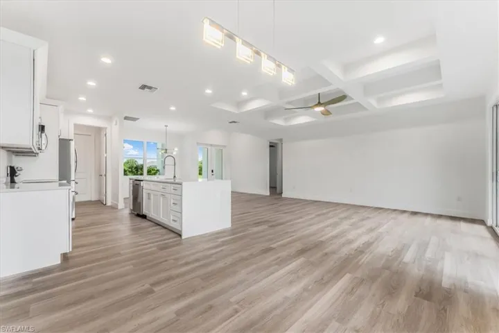 Unfurnished living room featuring recessed lighting, coffered ceiling, ceiling fan, light wood-style flooring, and beam ceiling