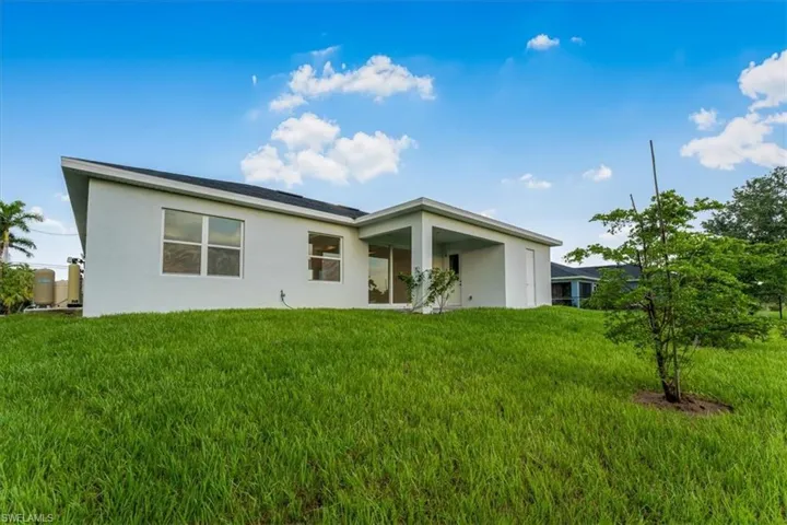 Back of property with stucco siding and a yard