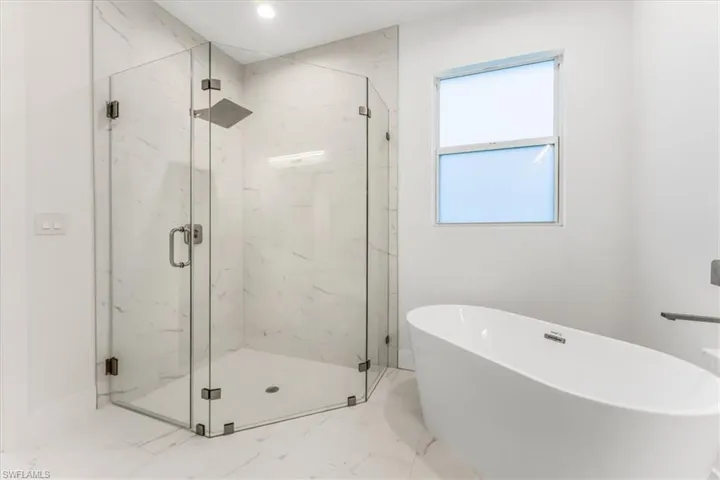 Bathroom with marble finish floors, a freestanding bath, a marble finish shower, and recessed lighting