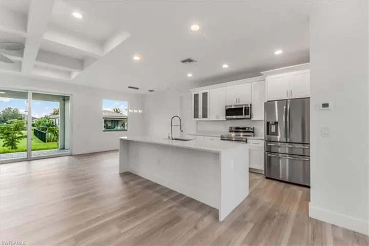 Kitchen with stainless steel appliances, a center island with sink, recessed lighting, light wood-style floors, and light countertops