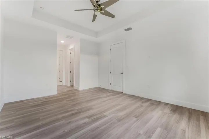 Unfurnished room featuring a tray ceiling, ceiling fan, light wood finished floors, and recessed lighting