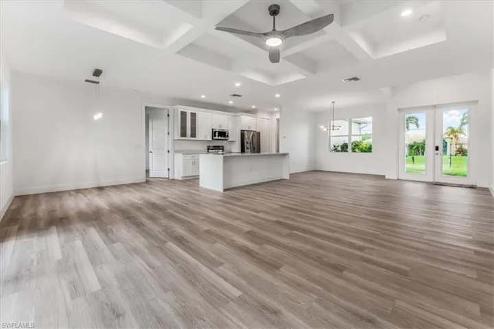 Unfurnished living room with coffered ceiling, light wood-style floors, ceiling fan, french doors, and recessed lighting